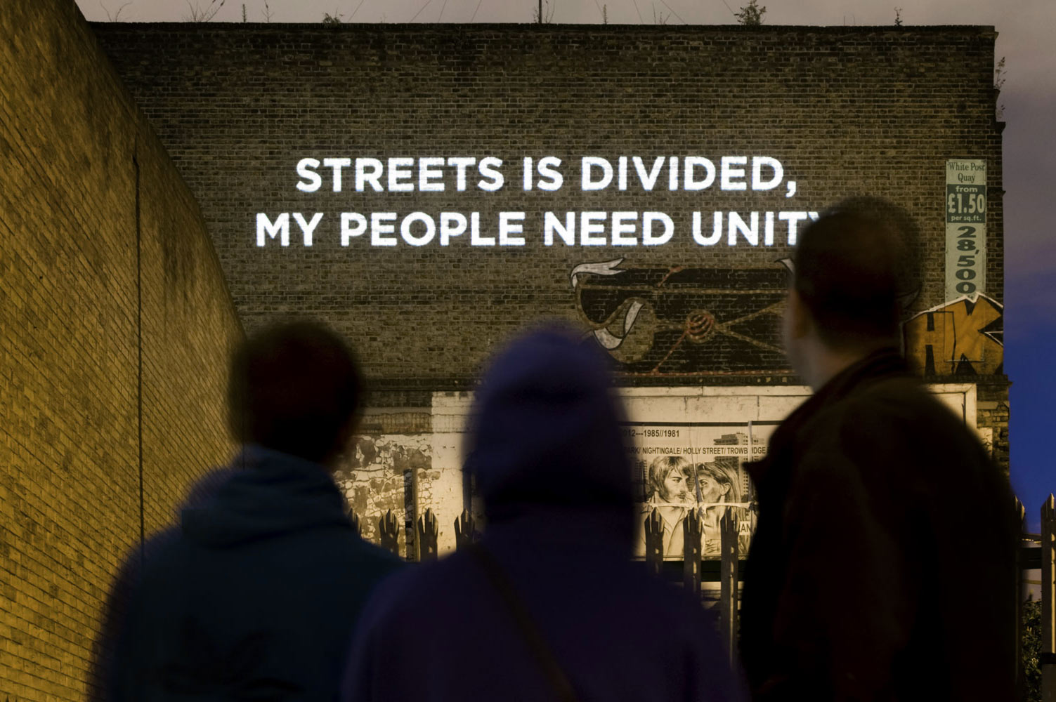 "Streets is divided, my people need unity" - Song lyrics projected on the side of a building photographed by James Robertshaw