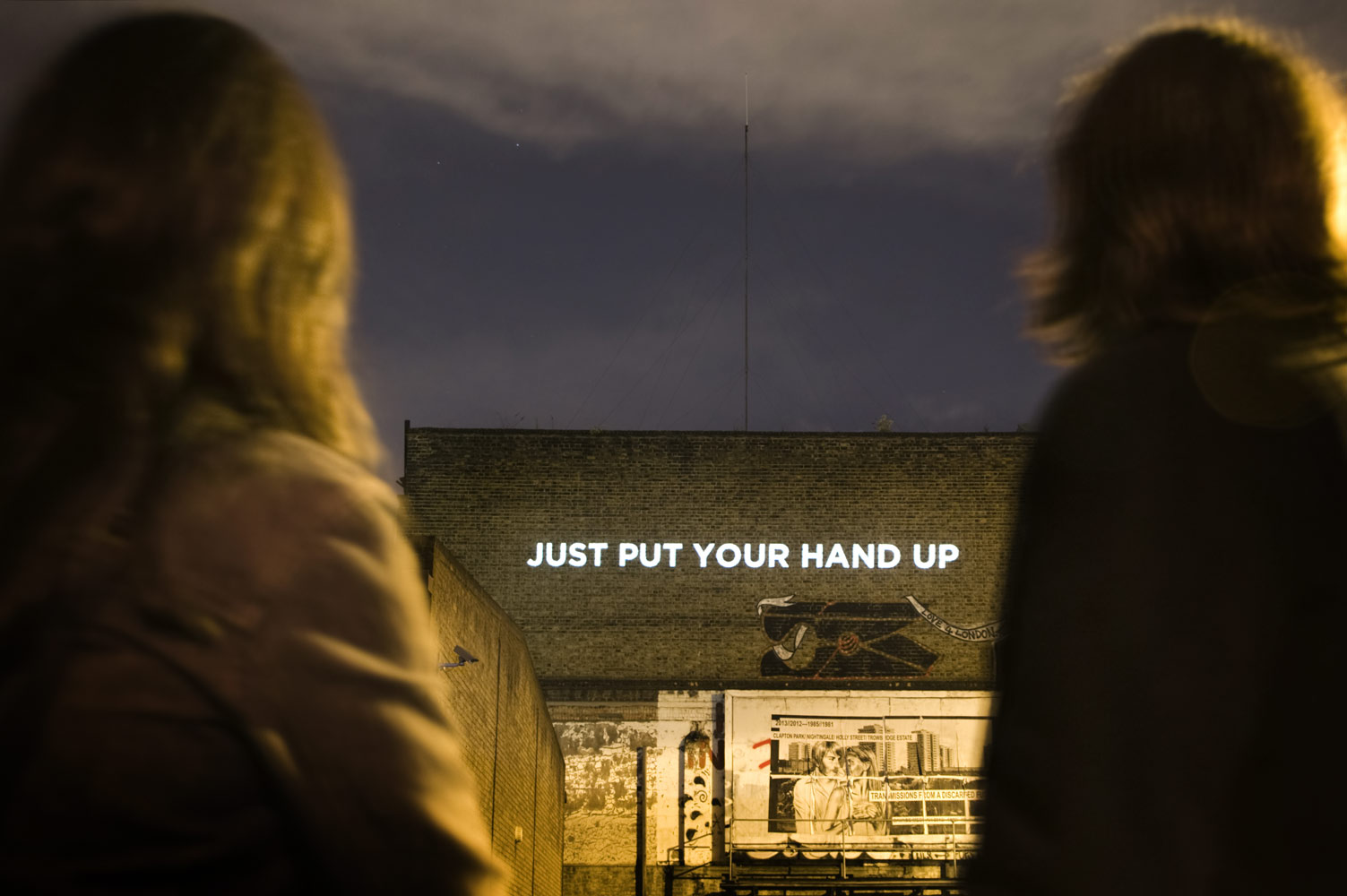 "Just put your hand up" - Song lyrics projected on the side of a building photographed by James Robertshaw