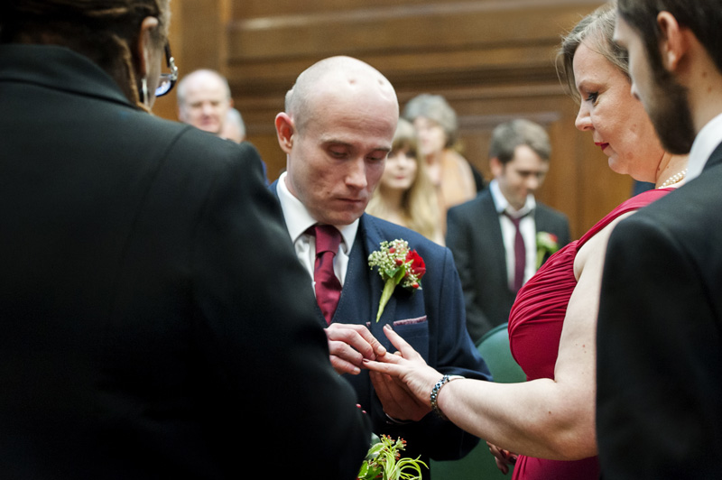 Groom placing ring on bride's finger at Camden Town Hall wedding