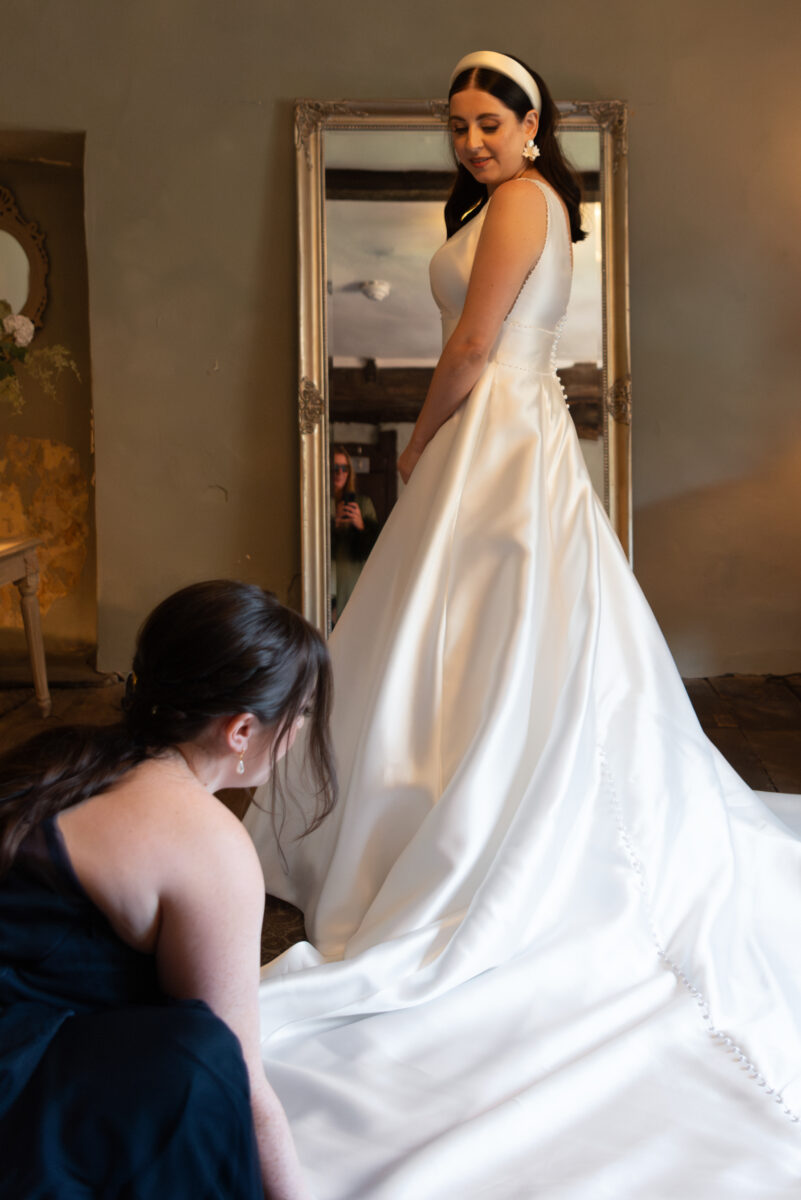 Bridesmaid adjusting bride's dress by Pilgrim's Rest wedding photographer, James Robertshaw