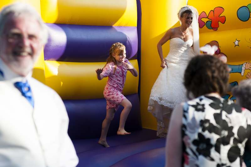 Bride on bouncy castle at Cooden Beach Hotel wedding reception by Sussex wedding photographer James Robertshaw