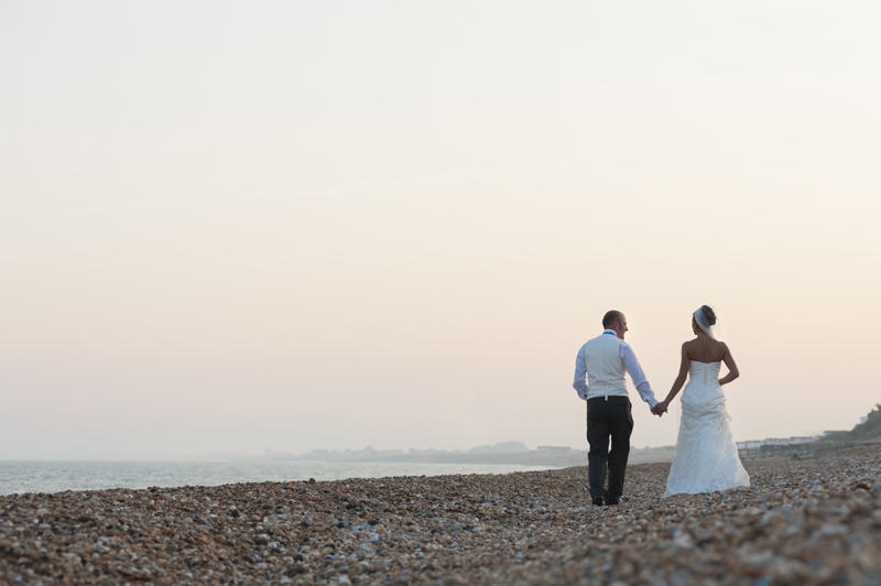 Couple walking on beach at Cooden Beach Hotel wedding reception by Sussex wedding photographer James Robertshaw