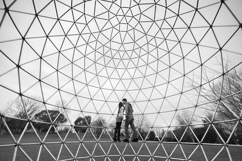 Couple kissing inside steel sphere structure- natural couple photography by James Robertshaw