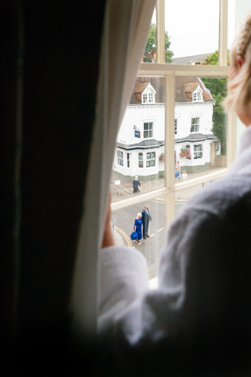 Bride looking uput hotel room window by Windsor Guildhall wedding photographer James Robertshaw