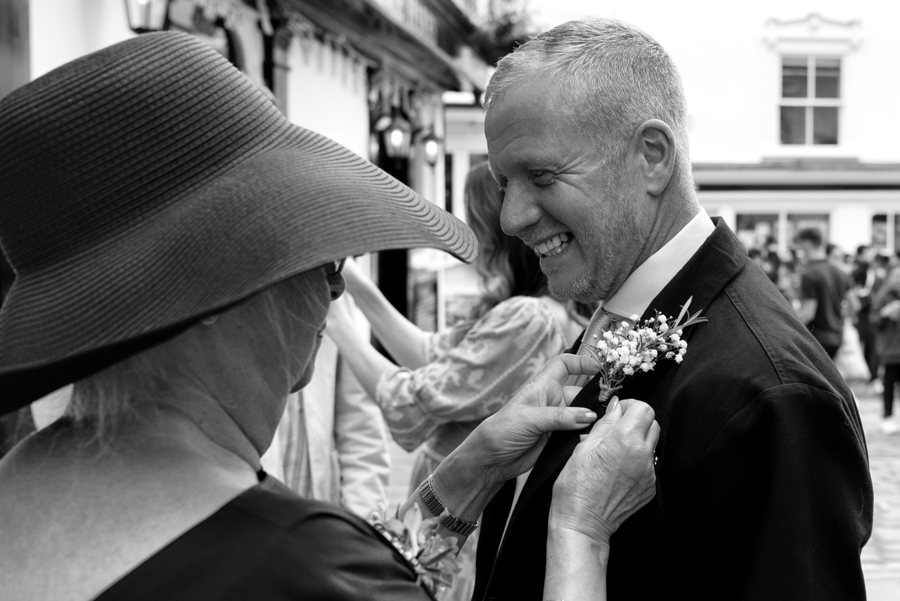 Mother of the bride attaching buttonhole to groom 